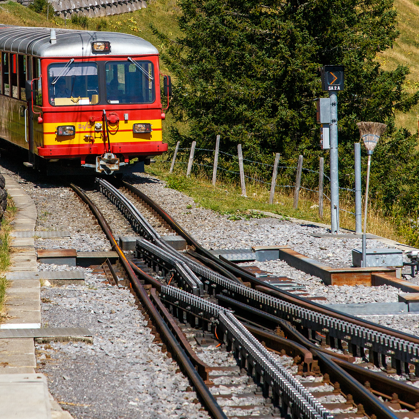 Deteilbild einer Weiche der zweilamelligen hochliegenden Zahnstangen vom System Abt, hier der tpc BVG - Chemin de fer Bex–Villars–Bretaye, hier am 10 September 2023 beim Haltepunkt Bouquetins auf 1.758 m ü. M, der Strecke 128 (Villars-sur-Ollon–Col-de-Bretaye).Geführt von dem Steuerwagen tpc BVB Bt 54 kommt der tpc BVB Pendelzug (Steuerwagen BVB Bt 54, Personenwagen tpc BVB B 51 und die BVB HGe 4/4 32 „Villars“) vom Bergbahnhof Col-de-Bretaye (1.808 m ü. M.) hinab.

Die tpc Strecke BVB, deutsch Bex–Villars–Bretaye-Bahn, ist eine 17 km lange Schmalspurbahn in der Spurweite 1.000 mm mit gemischtem Adhäsions- und Zahnradbetrieb. Das 4,65 km Teilstück (BAV-Strecke 128) von Villars-sur-Ollon (1.252 m ü. M.) auf den Col-de-Bretaye (1.808 m ü. M) ist vollständig mit einer Zahnstange System Abt versehen und hat eine maximale Steigung von 170 Promille.