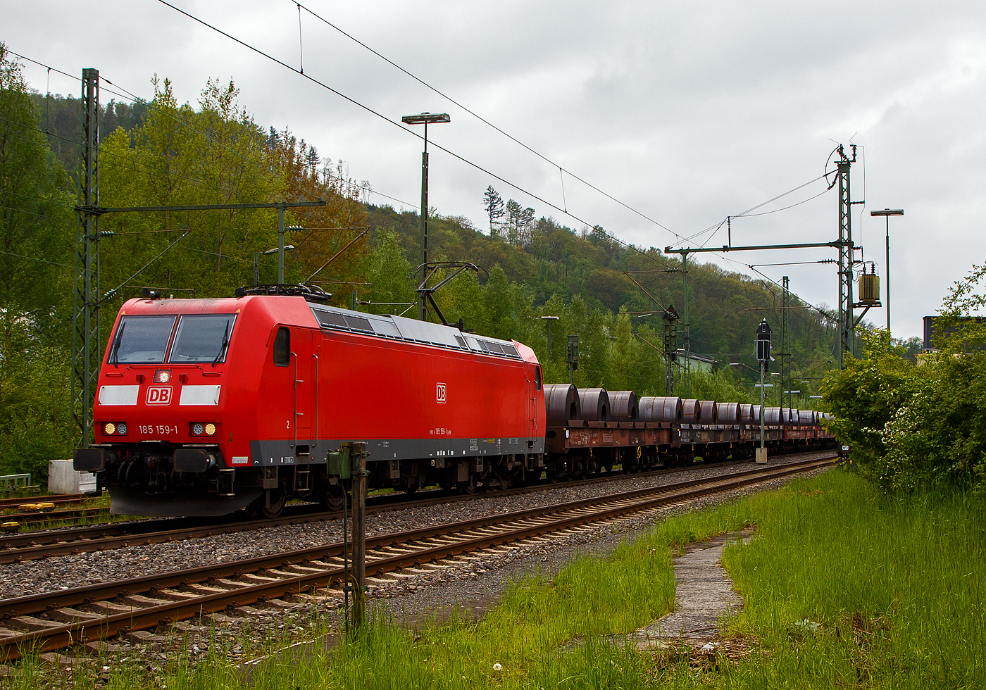 Die 185 159-1 (91 80 6185 159-1 D-DB) der DB Cargo AG fährt am 11.05.2023, mit einem Warmband-Coilzug (offene sechsachsige Wagen der Gattung Sahmms etc.), durch Niederschelden in Richtung Siegen bzw. Kreuztal.

Die TRAXX F 140 AC1wurde 2003 von der Bombardier Transportation GmbH in Kassel unter der Fabriknummer 33632 gebaut.
