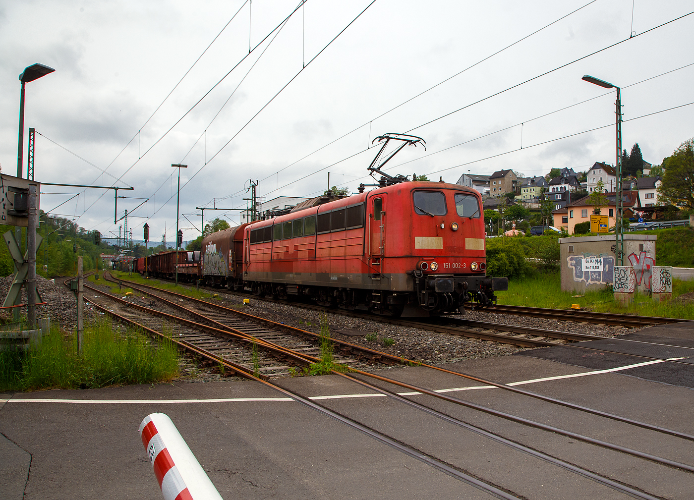 Die an die DB Cargo AG vermietete Railpool 151 002-3 (91 80 6151 002-3 D- Rpool) fhrt mit einem gemischten Gterzug am 11.05.2023 durch Niederschelden (hier beim B 343 – km 112,183 der Siegstrecke) in Richtung Siegen.

Die Lok wurde 1973 von Krupp in Essen unter der Fabriknummer 5174, der elektrische Teil ist von AEG unter Fabriknummer 8820, gebaut, und an die Deutsche Bundesbahn geliefert. Bis zum 31.12.2016 gehrte sie zur DB Cargo AG. Zum 01.01.2017 wurden je 100 sechsachsige elektrische Altbau-Lokomotiven der Baureihen 151 und 155 an ein Konsortium aus dem Lokvermieter Railpool verkauft. Die DB Cargo mietet daraufhin 100 Loks von Railpool wieder an. Die anderen Maschinen werden dem freien Markt angeboten.

Diese sechsachsigen Loks (Co’Co’) sind immer noch starke Zugpferde, und so manche moderne Lok hat nicht diese Leistungsfhigkeit. Mit einer Stundenleistung von 6.288 kW (8.550 PS) bei 92 km/h und einer Anfahrzugkraft von 395 kN knnen diese Loks 3.000 t Zge bei 3 ‰ Steigung noch mit einer Dauergeschwindigkeit 75 km/h ziehen, bei 2.000 t Zgen sind es 100 km/h.