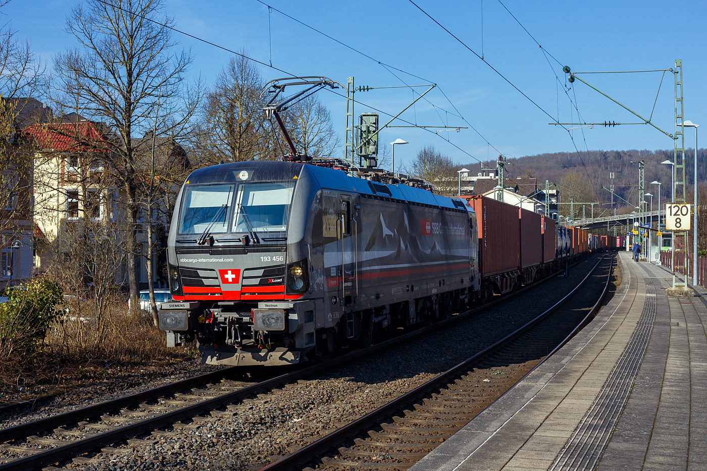 Die an die SBB Cargo International AG vermietete mit „XLoad“ ausgestattete 193 456  Schweizer Bahnhof Basel  (91 80 6193 456-1 D-SIEAG) der SüdLeasing GmbH, Stuttgart (eingestellt in Deutschland durch Siemens) fährt am 18 Februar 2025 mit einem KLV-Zug, durch Kirchen (Sieg) in Richtung Köln.

Die Multisystemlokomotive Siemens Vectron MS wurde 2024 von Siemens Mobilitiy in München-Allach unter der Fabriknummer 23784 gebaut und am 12.09.2024 ausgeliefert. Sie wurde in der Variante A40-1a ausgeführt und hat so die Zulassung für Deutschland, Österreich, die Schweiz, Italien, die Niederlande und Belgien (D / A / CH / I / NL / B). Sie verfügt über eine Leistung von 6,4 MW (160 km/h) und ist neben den nationalen Zugsicherungssystemen mit dem Europäischen Zugsicherungssystem (ETCS BL3) ausgestattet. Zudem ist sie mit der neuen Ausrüstungspaket XLoad ausgestattet. 

Das neue XLoad Ausrüstungspaket für Vectron:
XLoad ist ein Ausrüstungspaket für Vectron, welches künftig mitbestellt, aber auch bei bereits ausgelieferten Vectron Loks nachgerüstet werden kann. Das Feature verbessert die Reibwertausnutzung und ermöglicht dadurch höhere Anhängelasten. Zudem reduzieren die Fahreigenschaften, die das Feature bewirken, den Verschleiß von Rad und Schiene.

Aktuell sind die Schweizer Vectron-Lokomotiven (SBB Cargo und BLS Cargo) in der Regel in Doppeltraktion unterwegs. Die Steigungen und Rampen der Schweizer Berge sind vor allem bei schlechten Witterungsbedingungen nicht ohne. Eine Lokomotive muss auch bei geringerem Schlupf genügend Traktion auf die Schienen bringen, um alle Güter sicher und zuverlässig ans Ziel zu bringen. Ein effizienter Weg aus dieser «Misere» ist die für Vectron entwickelte Zusatz-Funktion «XLoad». Den erfolgreichen Beweis trat eine SIEMENS Testlokomotive im Frühjahr 2022 bei der SBB Cargo International und bei der BLS Cargo eindrücklich an. 

Für SBB Cargo International bewies die Test-Lokomotive am Bözberg und für BLS Cargo an der Nordrampe des Lötschbergs ihre enorme Zugkraft. 
Vectron meisterte im Frühjahr 2022 die lange 12‰-Steigung des Bözbergs mit einer Anhängerlast von 2.000 Tonnen bravourös. Bei den nächtlichen Testfahrten zeigte sich eindrücklich die enorme Zugkraft der Lokomotive. 

Am Lötschberg wurden bei der BLS Cargo steigungsmäßig noch ein paar Promille draufgepackt. Mit 1.020 Tonnen im Gepäck bewältigte die Vectron-Lokomotive mit XLoad-Feature die 27‰-Steigung der Nordrampe ebenfalls meisterlich. Und auch diverse Anfahrtsversuche absolvierte der mit dem XLoad-Feature aufgerüstete Vectron problemlos. 

So bestellte die SüdLeasing GmbH (Stuttgart) im Auftrag der SBB Cargo International jüngst 20 Vectron Lokomotiven mit XLoad bei SIEMENS.