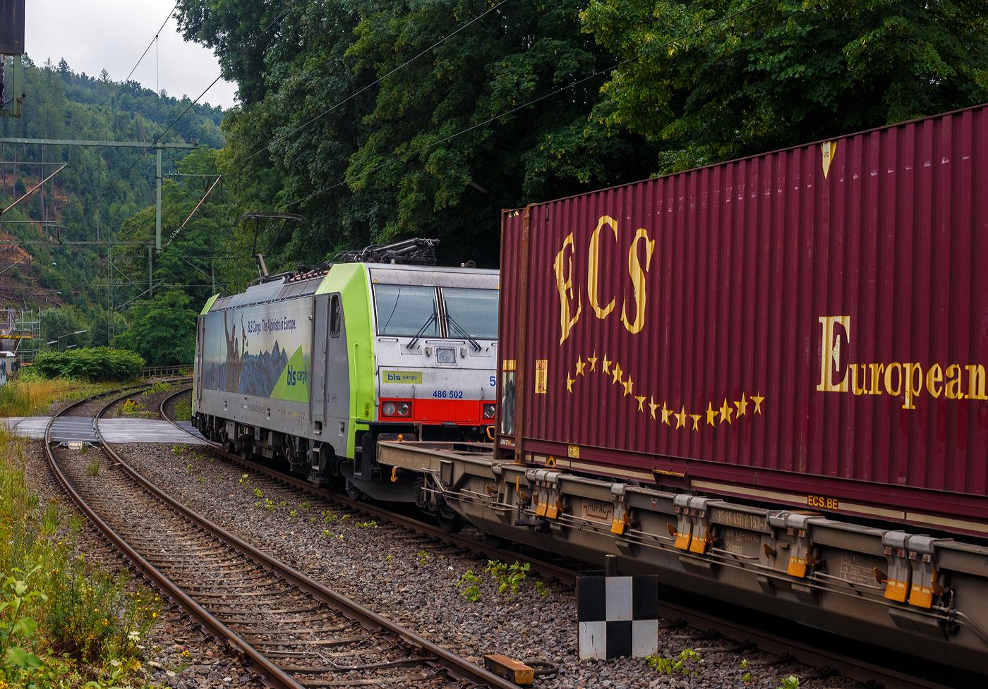 Die BLS Cargo 502, Re 486 502-8/E 486 502 SF  The Alpinists in Europa  (91 85 4486 502-8CH-BLSC) fährt am 07 Juli 2025 mit einem HUPAC KLV-Zug durch Kirchen (Sieg) in Richtung Köln.

Nochmals einen lieben Gruß an den netten Lokführer zurück.

Die TRAXX F140 MS wurde 2008 von Bombardier in Kassel unter der Fabriknummer 34401 gebaut und an die BLS Cargo AG (Bern) geliefert. Die Loks sind nur für die Schweiz, Deutschland, Österreich und Italien zugelassen.

Der Erfolg im Güterverkehr veranlasste die BLS zehn weitere TRAXX zu bestellen im Gegensatz zur ersten Serie TRAXX F140 AC1 mit der Bezeichnung Re 485 001 bis 485 020, die nur unter Wechselstrom fahren können, können die TRAXX F140 MS Re 486 501 bis 486 510 auch unter 3.000 Volt Gleichstrom eingesetzt werden. Bombardier hatte seit der ersten Lieferung Verbesserungen vorgenommen. Dabei wurde der Lokomotivkasten optimiert und die Traktionsausrüstung mit moderneren Komponenten versehen. Eine Nachbeschaffung wäre noch möglich gewesen, hätte aber dazu geführt, dass die Lokomotiven nicht auf dem neuesten Stand waren und nicht unter der Gleichstromfahrleitung eingesetzt werden konnten. Die eingebauten Zugbeeinflussungssysteme erlauben den Einsatz in Deutschland, Österreich, der Schweiz und Italien (DACHI). Anfänglich waren die Lokomotiven in der Schweiz nur für den Einsatz auf Strecken mit konventioneller Zugbeinflussung und nicht auf ETCS Level 2 Strecken zugelassen. Die Re 486 können unter sich und mit den Re 485 und Lokomotiven der Baureihe 185/186 in Vielfachsteuerung eingesetzt werden. Mittlerweile nach Umbauten durch die BLS, können die Loks nun auch mit Re 465, sowie mit Siemens Vectron der BR 193 bzw. Re 475 in Mehrfachtraktion gefahren werden.

TECHNISCHE DATEN:
Spurweite: 1.435 mm (Normalspur)
Achsformel: Bo’Bo’
Länge über Puffer: 18.900 mm
Höhe: 4.385 mm
Breite: 2.978 mm
Drehzapfenabstand: 10.400 mm
Achsabstand im Drehgestell: 2.600 mm
Dienstmasse: 85 t
Höchstgeschwindigkeit:  140 km/h
Dauerleistung: 5.600 kW
Dauerzugkraft: 300 kN
Treibraddurchmesser: 1.250 mm
Stromsysteme: 15 kV 16,7 Hz, 25 kV 50 Hz Wechselstrom sowie 3 kV und 1,5 kV Gleichstrom
Antrieb: Tatzlager