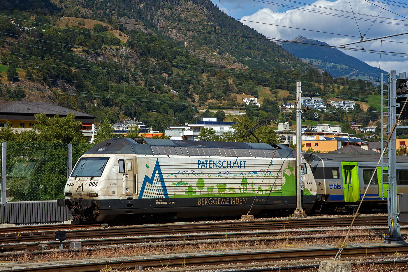 Die BLS Werbelok Re 465 008-1  Allegra , ex  Niederhorn , (91 85 4465 008-1 CH-BLS) mit Werbung Patenschaft für Berggemeinden steht am 07 September 2021 mit einem aus Einheitswagen III (EW III) bestehenden Zug in Birg.

Die Lok wurde 1994 von der SLM (Schweizerische Lokomotiv- und Maschinenfabrik) in Winterthur unter der Fabriknummer 5645 gebaut, der elektrische Teil ist von der ABB (Asea Brown Boveri).

Die Re 465 ist eine von der BLS Lötschbergbahn beschaffte elektrische, vierachsige Universallokomotive mit Umrichtertechnik. Sie ist eine Weiterentwicklung der Re 460 der SBB und gehört zur Lok-2000-Familie. Nach der Erstbestellung der BLS über acht Maschinen die 1994 gebaut wurden, folgten weitere 1997 zehn Loks (009–018) für den Huckepackkorridor. Diese Loks aus den 90er-Jahren sind für den Personen- wie für den Güterverkehr im Einsatz. Künftig werden sie auch beim Autoverlad und im Berner Oberland eingesetzt, nicht mehr im originalen Dunkelblau, sondern im leuchtenden BLS-Grün.

Zwischen 2019 und 2022 durchliefen alle 18 Loks des Typs Re465 ein Modernisierungsprogramm (Refit). Mit diesem Refit verlängert sich die Lebensdauer der rund 25-jährigen Loks um weitere 15 Jahre. Sie sind neu bis ins Jahr 2040 einsetzbar. Die modernisierten Lokomotiven sind gut zu erkennen, sie sind neu grün lackiert (diese noch nicht) und werden damit zur auffälligen und klar ersichtlichen BLS-Markenbotschafterin. Das Modernisierungsprogramm kostete insgesamt rund CHF 20 Millionen. Modernisiert wurden alle Loks in der BLS-Werkstätte Bönigen.

Im Personenverkehr zieht bzw. stößt die Re465 die GoldenPass-Express-Züge zwischen Interlaken Ost und Zweisimmen, im Güterverkehr wird sie in Mehrfachtraktion mit anderen Loks (TRAXX und Vectron) eingesetzt. Die Loks werden ab Ende 2023 auch beim Autoverlad eingesetzt und ersetzen damit die braunen Loks des Typs Re 425. Damit kann die BLS auf eine Neubeschaffung verzichten.

TECHNISCHE DATEN:
Spurweite:  1.435 mm (Normalspur)
Achsformel:  Bo’Bo’
Länge über Puffer:  18.500 mm
Drehzapfenabstand: 11.000 mm
Achsstand im Drehgestell: 2.800 mm
Höhe:  4.540 mm
Breite:  3.000 mm
Dienstmasse:  84 t
Höchstgeschwindigkeit:  230 km/h
Stundenleistung:  7.000 kW
Dauerleistung:  6.400 kW
Anfahrzugkraft:  300 kN
Treibraddurchmesser:  1.100 mm
Stromsystem:  Wechselstrom 15 kV 16,7 Hz
