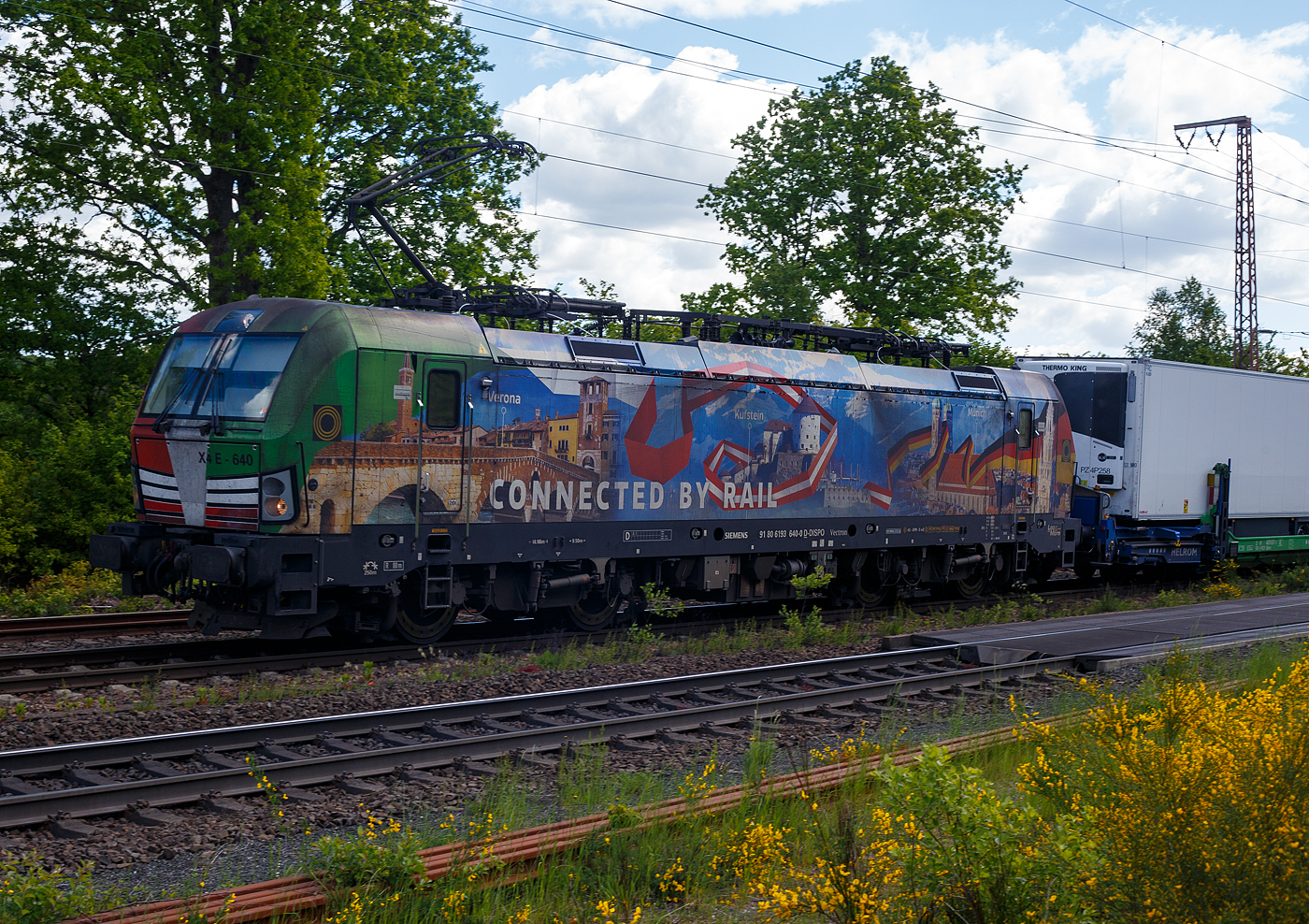 Die bunte und schöne Siemens Vectron MS X 4 E – 640 / 193 640-0 “Connected by Rail” (91 80 6193 640-0 D-DISPO) der Beacon Rail Capital Europe GmbH, München (BRCE / DISPO) fährt am 16 Mai 2025 mit dem HELROM Trailer Zug Wien – Düsseldorf, einem besonderen KV-Zug, durch Ruderdorf (Kr. Siegen), via Siegen, in Richtung Köln. Leider war die Lok hier nicht ganz sauber, zudem war eine Wolke vor der Sonne.

Die Siemens Vectron MS - 6.4 MW wurde 2016 von Siemens in München-Allach unter der Fabriknummer 22164 gebaut. Sie ist in der Variante A09 ausgeführt und hat so die Zulassungen für Deutschland, Österreich und Italien (D / A / I), daher trägt sie auch die Werbung München, Kufstein, Verona (Connected by Rail). Sie hat eine Höchstgeschwindigkeit von 160 km/h.

Die Lok wurde an die MRCE - Mitsui Rail Capital Europe GmbH in München ausgeliefert, seit September 2023 hat die Beacon Rail Metro Finance B.V. die Mitsui Rail Capital Europe B.V. (Amsterdam) und somit auch die Mitsui Rail Capital Europe GmbH im München übernommen, so firmiert sie nun als Beacon Rail Capital Europe GmbH, München (BRCE / DISPO).
