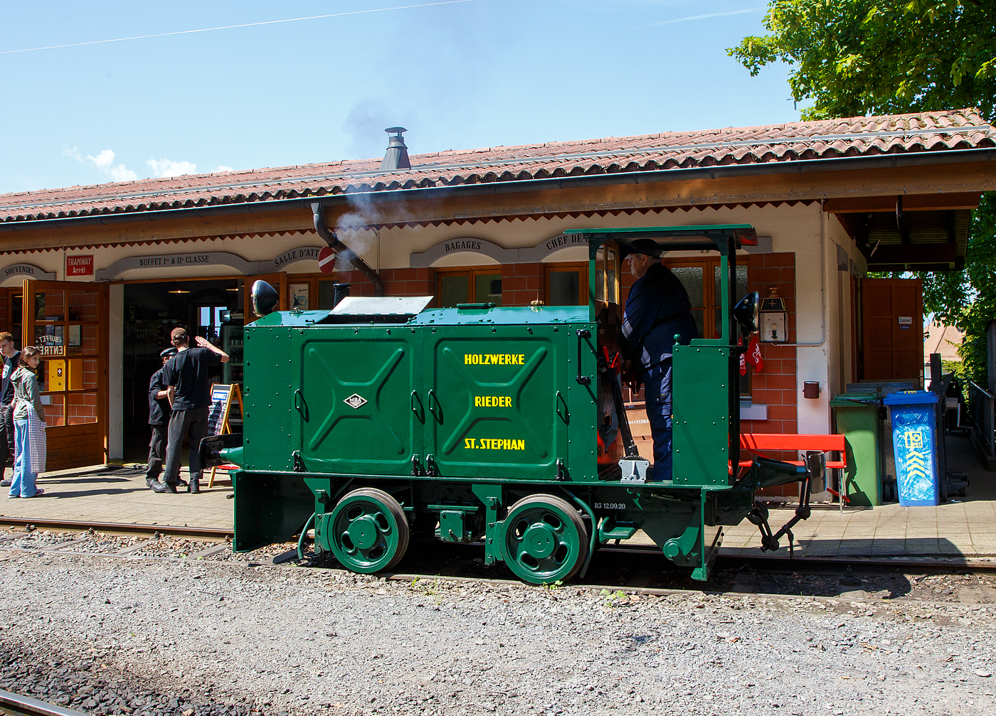 Die doch recht kleine ex MOB Schienentraktor Tm 2/2 Nr. 1, ex Holzwerk Rieder, der Museumsbahn Blonay-Chamby rangiert am 27.05.2023 im Museumsareal in Chaulin. 

Die kleine Diesellok, vom Typ O&K RL 2a wurde 1931 von Orenstein & Koppel im Werk Babelsberg unter der Fabriknummer 20200 gebaut und an die Grande Dixence SA für die Baustelle der ersten Dixence-Staumauer  geliefert, wo sie bis 1940 im Einsatz war. Im 1941 wurde sie dann von der Firma Mauerhofer & Zubner, für den Einsatz von Bauzügen beim Fahrleitungsumbau bei der MOB übernommen. 1950 wurde die kleine Lok an das Holzwerk Rieder in St. Stephan verkauft, diese Farbgebung trägt sie auch aktuell bei der BC. Die Lok trägt Fabrikschilder der MBA, wobei die Umbenennung der O&K in Maschinenbau und Bahnbedarf Aktiengesellschaft, vormals Orenstein & Koppel (MBA) erst im Februar 1940 erfolgte.

Die MOB (Montreux-Berner Oberland-Bahn / Montreux Oberland Bernois) kaufte die Lok dann 1979 wieder zurück und bezeichnete sie als Tm 2/2 1. Bei der MOB wurde sie für Rangierarbeiten, von Zementwagen auf Rollböcken in St. Stephan eingesetzt. Die Lok wurde 1995 von der MOB ausrangiert verbleib aber erst noch im Depot Montbovon. 2006 ging sie dann an die Museumsbahn Blonay-Chamby.

Die Lok hat einen 2-Zylinder-Orenstein & Koppel-Dieselmotor mit 22 PS (16 kW) Leistung, die Leistungsübertragung erfolgt über ein Zweigang-Konuskupplungs-Wendegetriebe mit stufenloser Geschwindigkeit Regulierung, über zwei Rollenketten auf die vordere Achse und von dieser über eine Rollenkette auf die hintere Achse. Das Zweigang-Konuskupplungsgetriebe ermöglicht zwei verschiedene Geschwindigkeitsstufen für beide Fahrtrichtungen. Dabei laufen immer beide Gänge im Eingriff, jeweils einer wird eingekuppelt. Eine einfache Wendeschaltung im Getriebe ermöglicht den Fahrtrichtungswechsel bei Stillstand der Lokomotive. Die einfache Bauart des Getriebes hat sich schon bei den Benzinloks bewährt und wurde bei fast allen O&K-Loks der unteren Leistungsklassen angewendet.

TECHNISCHE DATEN:
Spurweite: 1.000 mm (Meterspur)
Achsfolge: B
Länge über Puffer: 4.490 mm
Kastenlänge: 3.450 mm
Höhe: 2.270 mm
Breite: 1.240 mm
Achsabstand: 1.170 mm
Raddurchmesser : 550 mm
Eigengewicht: 7.000 kg
Leistung: 16 kW (22 PS)
Höchstgeschwindigkeit: 7 km/h
Achslager: Gleitlager

Die O&K Typenbezeichnung  RL  stand für  Rohöl  (= Diesel).

Anfang des 20. Jahrhunderts war es noch üblich bei und auf Großbaustellen Feld- oder Schmalspurbahnen zu bauen und zu betreiben. Heute durch Entwicklung von moderner und oft sehr schweren Baumaschinen und Muldenkipper eigentlich undenkbar.