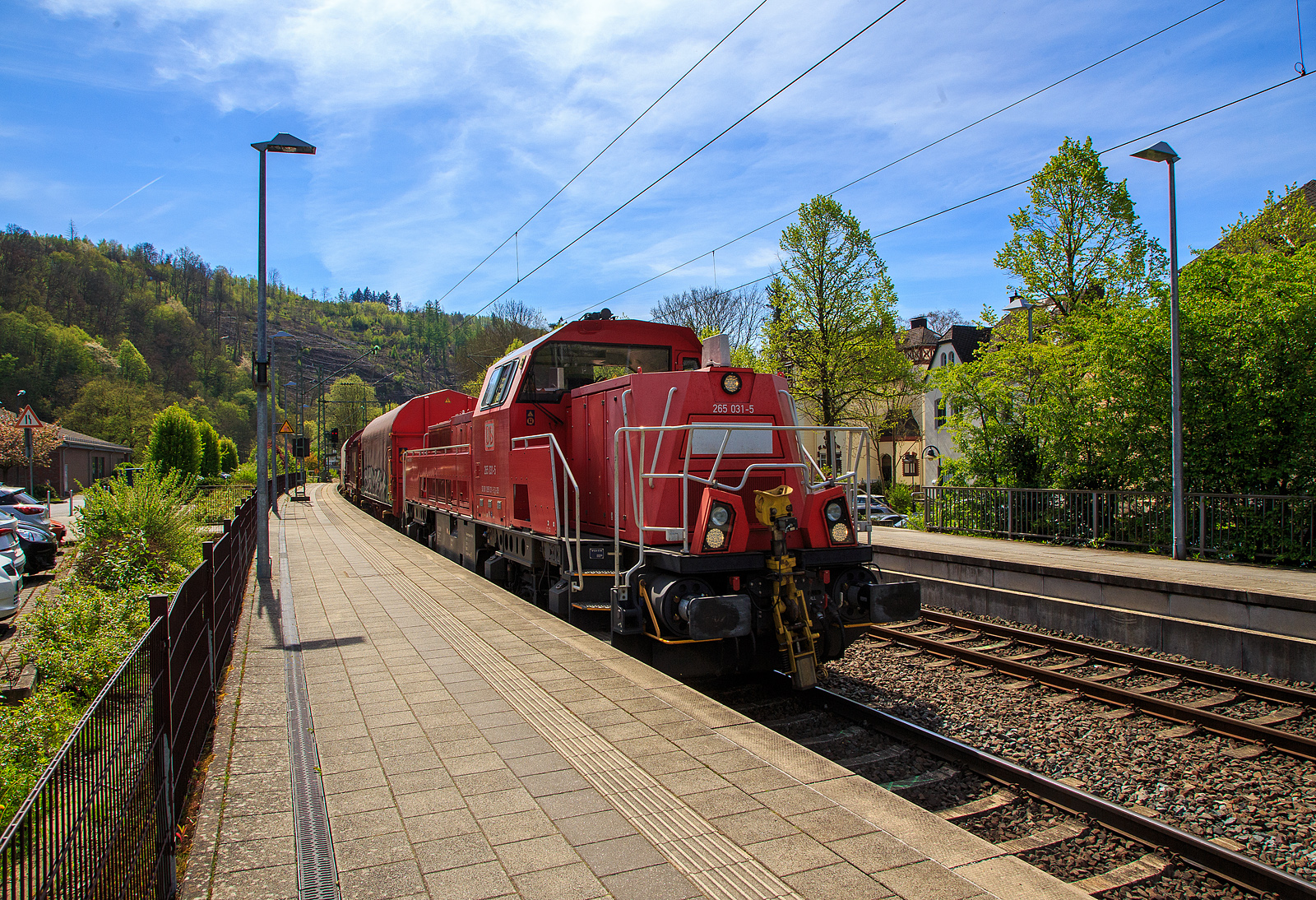 Die Kreuztaler 265 031-5 (92 80 1265 031-5 D-DB), eine Voith Gravita 15L BB der DB Cargo AG, fährt am 04.05.2023 mit einem Coilzug (Wagen der Gattung Shimmns) durch den Bahnhof Kirchen (Sieg) in Richtung Siegen bzw. Kreuztal.

Die Lok wurde 2013 von Voith in Kiel unter der Fabriknummer L04-18032 gebaut und an die DB Schenker (heute DB Cargo Deutschland AG) geliefert.

Die vierachsigen dieselhydraulischen Lokomotiven vom Typ Gravita 15L BB (BR 265) haben einen Leistung von 1.800 kW und habe somit 800 kW mehr Leistung als eine Gravita 10 BB (BR 261). Zudem sind sie über 1m länger als die kleine Schwester.

TECHNISCHE DATEN:
Spurweite: 1.435 mm
Länge über Puffer: 16.860 mm
Drehzapfenabstand: 8.200 mm
Drehgestell-Mittenabstand: 2.400 mm
größte Breite: 3.075 mm
größte Höhe über SOK: 4.273 mm
Raddurchmesser neu: 1.000 mm
kleinster bef. Gleisbogen: 80 m
Eigengewicht: 84 t
Kraftstoffvorrat: 5.000 l
Motor: V-12-Zylinder-Dieselmotor MTU 12V 4000 R43
Leistung: 1.800 kW bei 1.800 U/min
Getriebe: Voith L 5r4 zseU2
Anfahrzugkraft: 270 kN
Höchstgeschwindigkeit: 100 km/h
Tankvolumen: 5.000 l
Gebaute Stückzahl: 36
