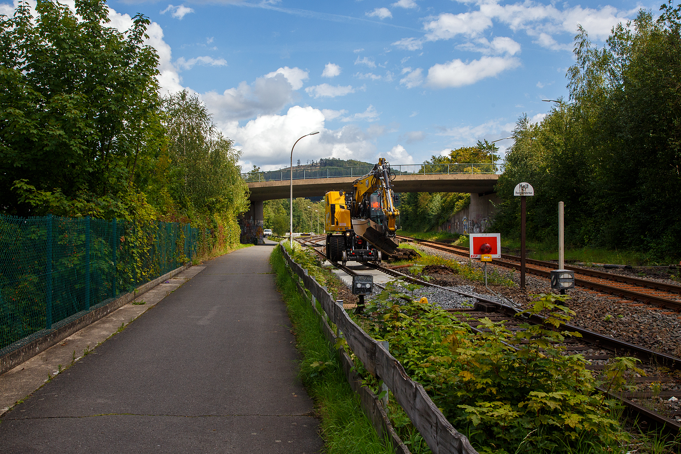 Die KSW (Kreisbahn Siegen-Wittgenstein) erneuert die ersten Gleismeter vom Anschlussgleis, zum Rangierbahnhof in Herdorf der Betriebsstätte FGE -Freien Grunder Eisenbahn (KSW NE447 / DB-Nr. 9275).

Hier am 16.08.2023 im Einsatz der Caterpillar CAT M323F Zweiwegebagger mit hydrostatischem Schienenradantrieb (Serien-Nr. RH600 189), Kleinwagen Nr. D-ZBM 99 80 9902 521-0 der ZEPPELIN Baumaschinen GmbH (Garching), ein Mietbagger vermietet an die Firma  W. Hundhausen Bauunternehmung GmbH (Siegen). Es werden die ersten Gleismeter vom Anschlussgleis erneuert, der Bagger ist bei der Einschotterung.
