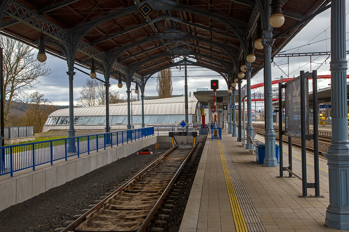 Die sehr schöne denkmalgeschützte Bahnsteigüberdachung vom Kopfgleis 1 vom Bahnhof Karlovy Vary (Horním nádražím) / Karlsbad (Oberer Bahnhof), hier am 17.04.2023. Sie ist das letzte Überbleibsel aus alten Zeiten,

Im Jahr 1945 wurden beide großen Karlsbader Bahnhöfe Ziel alliierter Bombenangriffe. So wurde das ursprüngliche Empfangsgebäude durch die Bombenangriffe alliierter Truppen im Zweiten Weltkrieg durch zerstört. Bereits 1945 wurde mit der Errichtung eines Ersatzgebäudes mit Hilfe von Freiwilligen begonnen. Das Provisorium blieb nach leichten baulichen Veränderungen bis zum Beginn der Modernisierung im Jahr 2015 bestehen.