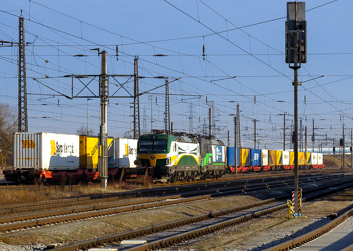 Die SIEMENS Vectron AC DPM (mit Diesel Power Modul) 471 006 (91 55 0471 006-1 H-GySEV) der GySEV Cargo - Györ-Sopron-Ebenfurti Vast Zrt. (Sopron/Ungarn) / Raaberbahn ist am 14 Januar 2025 beim Bahnhof Lambach (Oberösterreich) abgestellt. Dahinter steht noch eine weitere unbekannte SIEMENS Vectron AC der BR 193 der ELL - European Locomotive Leasing (Wien).

Die GySEV 471 006 wurde 2017 von der Siemens Mobility GmbH in München-Allach unter der Fabriknummer 22253 in der Variante B14 (Zulassungen für H / D / A / SK / RO / CZ) gebaut. 2018 durch Siemens in München-Allach dann das DPM (Diesel Power Modul) nachgerüstet. 

Diese Vectron Lokomotive ist als AC DPM – Lokomotive (Wechselstrom-Variante mit Dieselmodul für Rangieren ohne Fahrdraht) mit 6.400 kW konzipiert Im Dieselbetrieb beträgt die Leistung lediglich 180 kW (160 kW am Rad).
