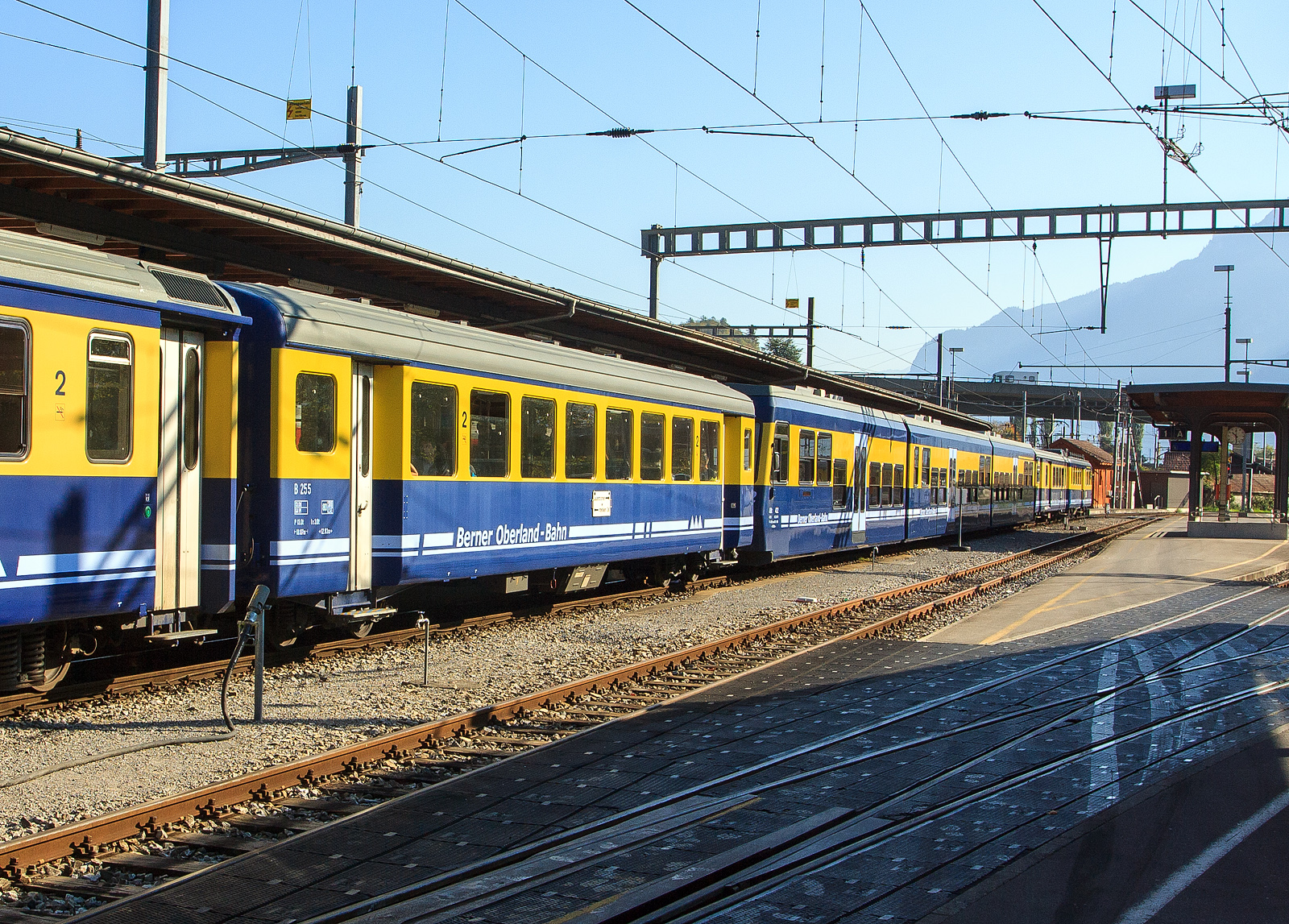 Eingereiht in einen BOB Pendelzug (Interlaken Ost – Grindelwald) am 02.10.2011 im Bahnhof Interlaken Ost, der BOB 2. Klasse Personenwagen B 255, ein Einheitswagen vom Typ SIG EW I bzw. Brünig Typ III (SIG1). 

Die SBB wählten für ihre schmalspurige Brünigbahn (heute Teil der Zentralbahn) nicht FFA, sondern SIG als Lieferantin der Einheitswagen. Deren Entwurf hielt sich äußerlich stärker an das normalspurige Vorbild, indem Plattform und Toilette außerhalb der Einstiege angesetzt wurden. Die Einstiegstüren wurden über den Drehgestellen angeordnet. Gemeinsam mit dem Entwurf der FFA war diesem Typ aber, dass der Sitzabstand offensichtlich vom Vorhandensein von „Schmalspurpassagieren“ ausging. Der Sitzteiler in der 2. Klasse ist mit 1.540 mm sogar noch geringer als beim FFA EW I ausgefallen. Da dies nicht ausreichte, wurden später bei der Modernisierung der Brünigbahn-Wagen zwei Sitzreihen weniger eingebaut, so dass der Sitzteiler (neu 1.760 mm) nicht mehr mit den Fenstern übereinstimmte. In der 1. Klasse wurden hingegen ein Sitzabstand von 2.055 mm geboten. Die Fenster wurden, wiederum gleich wie bei der Normalspur, für beide Wagenklassen mit 1.200 mm gewählt.

Der Beschaffung bei der SIG schlossen sich auch die BOB und die BVZ an. Die FO und die MOB, als einzige Adhäsionsbahn verzichteten auf eine Endplattform, was den Wagen ein eigenartiges unsymmetrisches Aussehen gab. Die MOB ließ darüber hinaus auch die Faltenbälge weg. Die vier Privatbahnen gönnten den erste Klasse Passagieren einen ungehinderten Blick auf das Bergpanorama durch 1400 mm breite Fenster, dafür wurde der Sitzabstand im A auf 1.932,5 mm und im AB auf 1.917,5 mm reduziert, was die Proportionen doch sichtlich veränderte. Der Erstklasswagen wurde bei gleicher Platzzahl wie am Brünig um einiges kürzer.

Auf Grund der unterschiedlichen Kupplungssysteme ist die Länge über Puffer ein ungeeignetes Vergleichskriterium. Die Kastenlänge beträgt bei allen Brünigbahn Wagen sowie bei den B für BOB und BVZ 17.3 m. Der A von BOB und BVZ wurde dagegen nur 16,485 m lang. Die reduzierte Abteillänge erlaubte es dafür beim Bau von AB, vier erste Klasse Abteile und drei zweite Klasse Abteile unterzubringen, anstatt der umgekehrten Zahlen beim AB für die Brünigbahn.

Da der Wagen für den Einsatz auf Zahnradbahnen konzipiert ist, wurde möglichst gewichtssparend gebaut. Es gibt (außer früher bei den Brünig AB) nur ein WC. Der Kasten ist aus Aluminium. Allerdings wurde bei den ersten elf Wagen (Prototyp für den Brünig und die ersten zehn Wagen für die BOB) die Legierung Unidur gewählt. Diese hatte nicht die erforderliche Festigkeit, weshalb von den elf Wagen nur noch fünf in Betrieb gehalten werden konnten.

2015 wurden 16 überzählige Wagen der Zentralbahn (zb) nach Benin und Niger verkauft.

TECHNISCH DATEN:
Baujahre: 1966 bis1971
Spurweite: 1.000 mm
Länge über Puffer : 18.070 mm
Wagenkastenlänge: 17.300 mm
Drehzapfenabstand: 12.830 mm
Drehgestelle: SIG-66 mit Bremszahnrad
Eigengewicht: 13 t
Sitzplätze: 64 in der 2. Klasse
Zul. Höchstgeschwindigkeit: 80 km/h
Zugelassen für Netz der: Brünig, BOB und LSE
