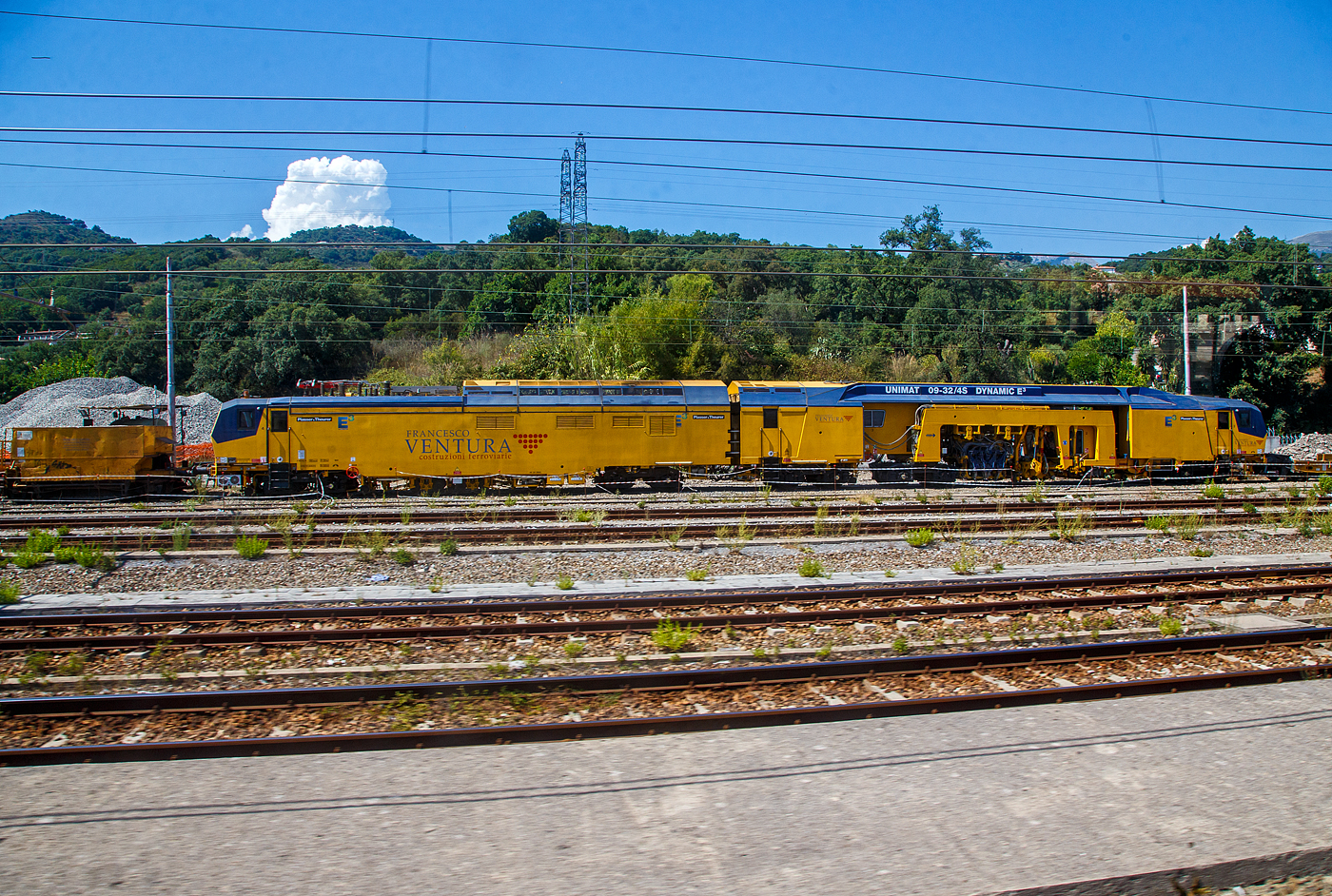 In Italien laufen schon die hochmodernen Maschinen mit Hybrid-Antriebssystem E³...
Hier ist die Plasser & Theurer UNIMAT 09-32/4S Dynamic E³ der Francesco Ventura Costruzioni Ferroviarie S.r.l. (Paola/Italien), gehört zur Salcef Group, am 16.07.2022 beim Bahnhof Sapri (Kampanien) abgestellt. Aufnahme aus einem IC heraus.

Das Plasser & Theurer Hybrid-Antriebssystem E³ treibt eine große, kontinuierlich arbeitende Weichenstopfmaschine an. Das neue Hybrid-Antriebskonzept E³ treibt die Maschine entweder durch einen Diesel- oder durch einen Elektromotor an, und zwar durch Nutzung der elektrischen Energie aus dem Fahrdraht (eine Nutzung durch Akkupower ist auch möglich). Beide Motoren erzeugen den Hydraulikdruck für alle Systeme, vom Fahrantrieb für Überstell- und Arbeitsfahrt bis zu den Arbeitsaggregaten. 

E³-Maschinen von Plasser & Theurer stehen für: Economic – Ecologic – Ergonomic.
