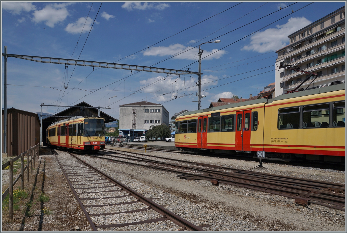 Links, angeschnitten, wartet in Orbe der  Karlsruher  Triebwagen Be 4/8 N� 3 (94800 450 003-9 D-TVYS) auf die Abfahrt nach Chavornay, w�hrend rechts im Bild der zweite Triebwagen Be 4/8 N� 4 im  Reservedienst  steht.

5. Juli 2025