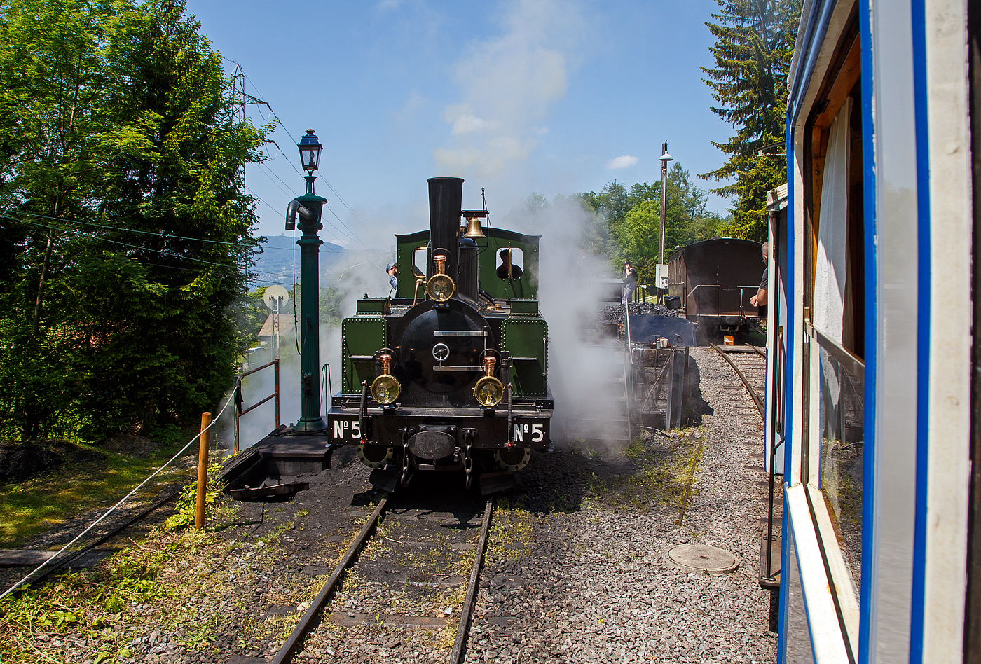 Museumsbahn-Romantik pur – Pfingsten 2023 (Samstag 27. bis Montag 29. Mai 2023) fand bei der Museumsbahn Blonay–Chamby das Schweizer Dampffestival 2023 / Festival suisse de la Vapeur 2023 statt.

Bei der Dampflok-Wartungsstelle der Museumsbahn Blonay–Chamby beim Museumsareal in Chaulin steht am 27.05. 2023 die G 3/3 LEB N° 5  Bercher  der Museumsbahn zum Kohlefassen. Links die Strecke 115 der MVR hinab nach Blonay, wir fahren mit dem ex MOB BCFe 4/4 11 rechts das Stichgleis zum Museum bzw. Depot hinauf.

Die ex LEB Nr. 5  Bercher  (Lausanne–Echallens–Bercher-Bahn) wurde 1890 von der Elsässische Maschinenbau-Gesellschaft Grafenstaden (später Société Alsacienne de Constructions Mécaniques) unter der Fabriknummer 4172 gebaut und an die Lausanne–Echallens–Bercher-Bahn geliefert. Die EMBG hatte auch zwei Jahre zuvor die baugleiche Nr. 2 geliefert. Die beiden dreiachsigen Tenderlokomotiven trugen die Hauptlast des Verkehrs, bis in den Jahren 1903 und 1905 zwei baugleichen Tenderlokomotiven, die G 3/3 6 „Gros-de-Vaud“ und G 3/3 7 „Talent „durch die Schweizerische Lokomotiv- und Maschinenfabrik (SLM) in Winterthur abgeliefert wurden. 

Von der YSteC konnte die LEB 1920/1921 die drei 1893 ebenfalls durch die EMBG gebauten Mallet-Lokomotiven G 2x2/2 Nr. 1 bis 3 gebraucht übernehmen. Nun waren die G 3/3 Nr. 2 und 5 nicht mehr gefragt. Während die G 3/3 2 „Échallens“ bereits 1929 verschrottet wurde (seit 1920 war sie bereits abgestellt), die G 3/3 Nr. 5  Bercher  hatte es da etwas besser, sie wurde 1934 an die Firma Energie de l’Ouest Suisse (EOS) für die Baustelle der Staumauer Grande-Dixence verkauf. Nach dem die Arbeiten 1935 erledigt sind geht sie bei der EOS außer Betrieb. Im Jahr 1939 verlässt die Schweiz und geht nach Vorarlberg in Österreich, zu einer Baufirma. Die Baufirma verschenkte 1967 die Lok und sie wurde, wie viele andere Dampflokomotiven zu dieser Zeit, auf einem Kinderspielplatz in der Stadt Feldkirch aufgestellt. Das Ausstellungsobjekt weckte die Aufmerksamkeit einiger Mitarbeiter der Museumsbahn Blonay–Chamby (BC), denen es gelang 1973 diese Lokomotive im Tausch gegen eine andere Lok zu erwerben.

Nach einer Aufarbeitung war die Lokomotive 1985 bis 2005 in Betrieb. Dann musste sie abgestellt werden. 2013/2014 wurde die Lokomotive ein zweites Mal durch die Museumseisenbahner aufgearbeitet. Seit dem Frühling 2015 ist die zweitälteste Schmalspur-Dampflokomotive der Schweiz, die älteste ist die G 3/4 1 „Rhätia  der Rhätischen Bahn (RhB), nach dem Abschluss der Revisionsarbeiten wieder in Betrieb.

TECHNISCHE DATEN der LEB G 3/3 N° 5  Bercher :
Baujahr: 1890
Spurweite: 1.000 mm
Achsformel: C
Länge über Puffer: 6.830 mm
Achsabstand: 1.800 mm (950mm / 850 mm)
Dienstgewicht: 20,4 t
Anzahl der Zylinder: 2
Zylindergröße: Ø 270 mm x 370 mm Kolbenhub
Treibraddurchmesser: 810 mm
Höchstgeschwindigkeit: 25 km/h
Stundenleistung: 150 PS
Kesselüberdruck: 12 bar
Kohlevorrat: 0,8 t
Wasservorrat: 2,2 m³

Die Lausanne–Echallens–Bercher-Bahn, abgekürzt LEB, französisch Chemin de fer Lausanne–Echallens–Bercher, ist eine meterspurige Privatbahn. Die knapp 24 Kilometer lange Strecke führt vom Stadtzentrum von Lausanne (Flon) durch die nördlichen Vororte und weiter nach Echallens und Bercher im Gros de Vaud, dem Waadtländer Hinterland. Die LEB ist eine moderne Vorortbahn, die in Lausanne teilweise unterirdisch verkehrt. Die Züge fahren alle 30 Minuten (zwischen Echallens und Bercher gibt es einige wenige Taktlücken am Vormittag). Werktags wird ein Viertelstundentakt bis Cheseaux angeboten. Von Montag bis Freitag verkehren in Lastrichtung einige beschleunigte Hauptverkehrszüge.
