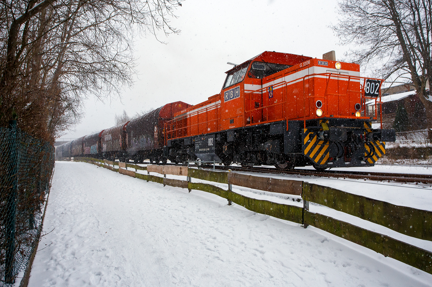 Nun hat es angefangen kräftig zu schneien, die HLB RB 96 „Hellertalbahn“ ist durch und die zurzeit an die KSW (Kreisbahn Siegen-Wittgenstein) vermietete RBH 802 „Ruhrpott Sprinter“ / 275 802-3 (98 80 0275 802-3 D-RBH), eine MaK G 1206 der RBH - RAG Bahn und Hafen GmbH (Gladbeck), kann die Fahrt mit einem Übergabegüterzug beginnen. Der Zug geht via Betzdorf/Sieg und Siegen zum Gbf der DB Cargo in Kreuztal.

Die MaK G 1206 wurde 1997 von der Siemens Schienenfahrzeugtechnik (SFT) in Kiel-Friedrichsort unter der Fabriknummer 1000901 gebaut und an die damalige RAG - Ruhrkohle AG, RAG Bahn- und Hafenbetriebe in Gladbeck als RAG 802 ausgeliefert. Sie war erst die zweite gebaute Lok der erfolgreichen Typs G 1206 aus dem 3. Typenprogramm. Im Jahr 2004 erfolgte die Umfirmierung der RAG in RAG Bahn und Hafen GmbH (RBH) und nach der Übernahme durch die DB Schenker Rail Deutschland AG (heute DB Cargo) erfolgte 2006 die Umfirmierung in RBH Logistics GmbH.