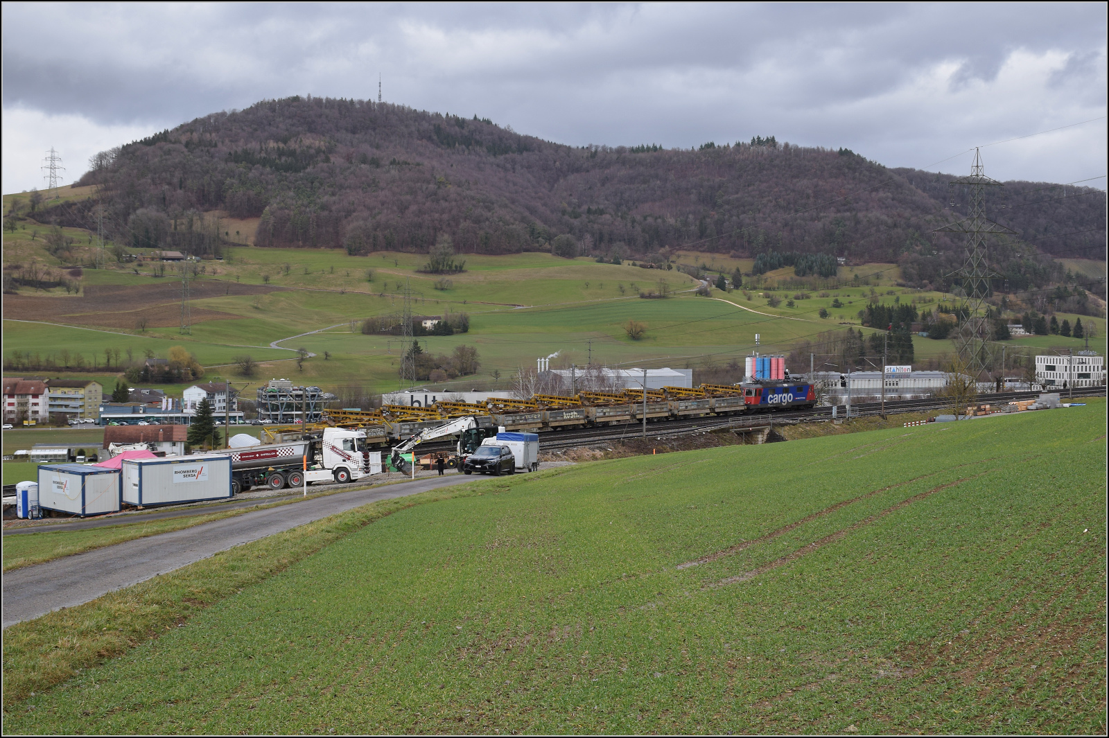 Schlechtwetter und ein Baustellendrama bei Frick. 

Re 420 337 f�hrt mit einem Bauzug zum B�zberg. Unterdessen wird es mit der Abscheppaktion auf der Baustelle ernst. Der realativ nahe Aufenthalt der Beobachterin erscheint mir aus der Ferne gef�hrlich. Es sollte aber nichts passieren, allerdings bewegte sich auch der LKW keinen Millimeter... Februar 2026.