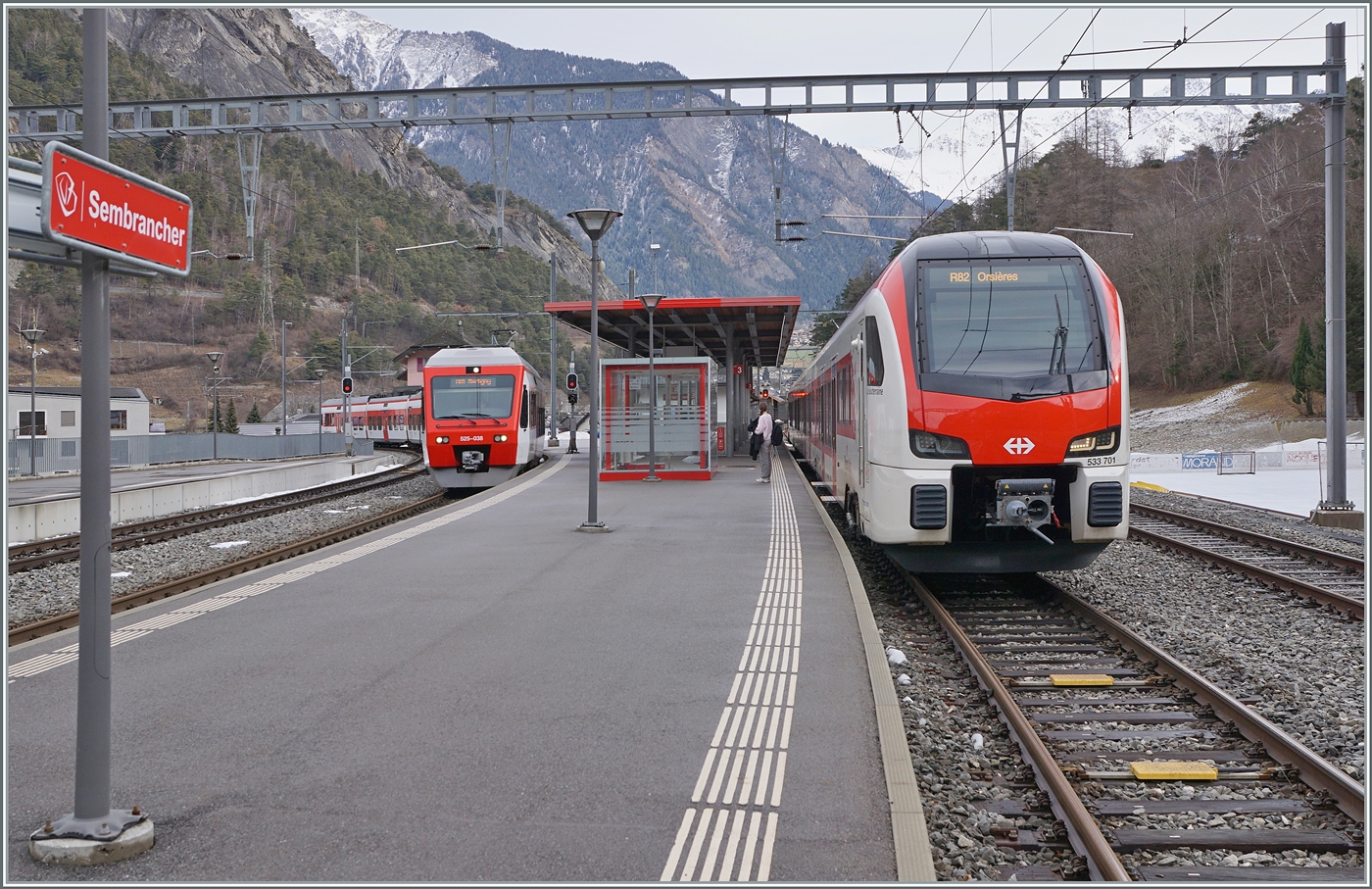 Sembrancher: der aus Orsières angekommene EVO RABe 5233 701 wir in Kürze nach Orsières zurück fahren, während auf Gleis 2 der Anschlusszug nach Martigny, bestehend aus zwei TMR RABe 525 NINA eintrifft. 

24. Jan. 2026