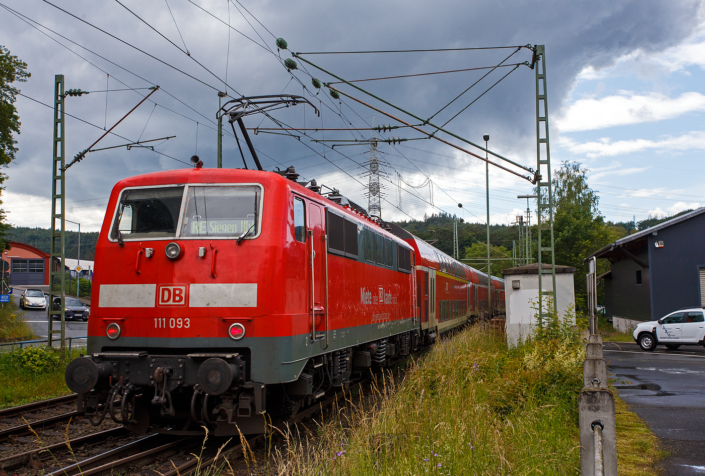 Steuerwagen voraus rauscht der RE 9 rsx - Rhein-Sieg-Express (Siegen – Köln – Aachen) am 12 Juni 2024 durch den Bahnhof Scheuerfeld (Sieg) in Richtung Köln. Hier im Nachschuss auf die schiebende 111 093-1 (91 80 6111 093-1 D-DB) der DB Regio NRW bzw. der DB-Gebrauchtzug. Die Zugzielanzeige ist hier falsch, es müsste eigentlich Aachen Hbf angezeigt sein, hier steht sie noch auf der Gegenrichtung.

Die Lok wurde 1978 von Krupp unter der Fabriknummer 5430 gebaut, der elektrische Teil wurde von AEG unter der Fabriknummer 8972 geliefert.