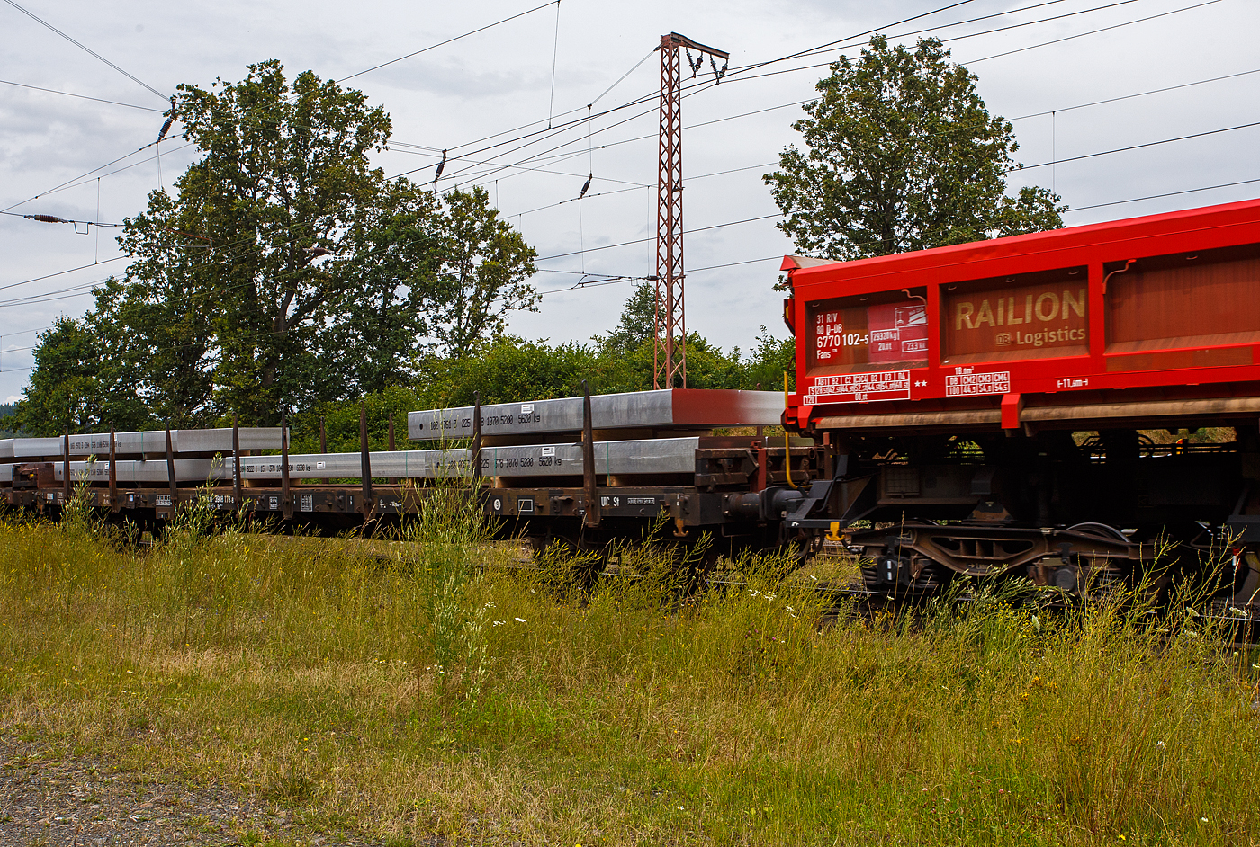 Vierachsiger Drehgestellflachwagen mit Rungen, Stirnwandklappen und klappbaren Ladeschwellen, jedoch ohne Seitenwandklappen, 31 80 3908 173-8 D-DB der Gattung Rs 684.2, der DB Cargo AG, am 19 Juli 2024 im Zugverband bei einer Zugdurchfahrt durch Rudersdorf (Kreis Siegen). Beladen ist der Wagen hier mit 9 Aluminium-Brammen mit einem Stückgewischt von 5.600 bis 6.600 kg. So ist der Wagen gemäß Lastgrenzenraster für die Streckenklasse C gut ausgeladen (aber nicht überladen). 

Der Wagen wurde 1972 von der Wagon Union (WU) in Berlin-Borsigwalde gebaut.

Mit einer Ladelänge von 18,50 m dienen diese Wagen zur Beförderung von schweren, langen Erzeugnissen der Eisen- und Stahlindustrie und Fertigbauteilen, Holz, Halbzeug, Fahrzeugen u.a.m. Für diese Transporte bieten wir Wagen in verschiedenen Ausstattungen an.

Der Wagen dient mit aufgeklappten Ladeschwellen zur Beförderung von schweren Walzprofilen und anderen sperrigen und schweren Gütern. Mit eingeklappten Ladeschwellen, also mit ebener Ladefläche, eignet er sich auch für die Beförderung schwerer Kettenfahrzeuge.

Vor den umlegbaren Stirnwandklappen sind je zwei absenkbare Rungen angeordnet. Der Wagen kann mit umgelegten Stirnwandklappen und abgesenkten Rungen gefahren werden. Die Höhe der umgelegten Stirnwandklappen über FO beträgt 38 mm. An jeder Längsseite des Wagens sind 8 Drehrungen angeordnet.

Der Fußboden besteht aus Kiefernbohlen mit den Abmessungen 70 x 180 mm. Er kann eine Radlast von 5,0 t aufnehmen. Im Fußboden sind 8 geteilte Ladeschwellen eingebaut. An einem Teil der Wagen ist in einem Drehgestell eine vom Boden aus bedienbare Feststellbremse eingebaut. Die Wagen haben eine Klotzbremse mit stufenlos, selbsttätiger Lastabbremsung. Die Bremskraft wird für jedes Drehgestell einzeln gesteuert. In jedem Drehgestell befindet sich ein Wiegeventil WM 10 und ein Doppelbremszylinder. Das Steuerventil ist im Wagenuntergestell angeordnet.

TECHNISCHE DATEN:
Erstes Baujahr der z. Z. ältesten Wagen: 1968
Spurweite: 1.435 mm (Normalspur)
Anzahl der Achsen: 4 in 2 Drehgestellen
Länge über Puffer: 19.900 mm
Drehzapfenabstand: 14.860 mm
Achsabstand in den Drehgestellen: 1.800 mm
Eigengewicht: 26.100 kg
Höhe Fußboden über SOK: 1.260 mm
Höhe der Ladeschwelle über FO: 70 mm
Max. Ladelänge: 18.500 mm
Ladefläche: 51,3 m² 
Maximale Ladegewicht: 54,5 t (ab Streckenklasse C)
Höchstgeschwindigkeit: 100 km/h (beladen) / 120 km/h (leer)
Kleinster befahrbarer Gleisbogenhalbmesser: R 35 m
Bremse: KE-GP-A (LL)
Bremssohle: IB 116
Intern. Verwendungsfähigkeit: RIV