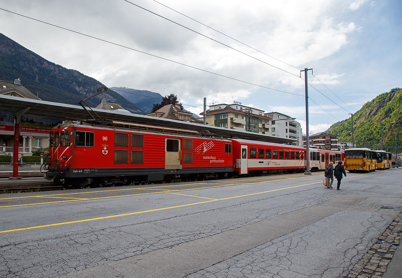 Von dem Gepäcktriebwagen Deh 4/4 II - 96  Münster   der 
Matterhorn-Gotthard-Bahn (MGB), ex FO 96  Münster   (Furka-Oberalp-Bahn), geschoben verlässt am 25.05.2023 der Regionalzug von Andermatt nach Visp den Bahnhof (Vorplatz) Brig.

Der Gepäcktriebwagen wurde 1984 von SLM (mechanischer Teil, Lokomotivkasten) und BBC (elektrische Ausrüstung) gebaut.