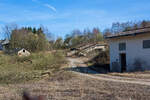 Die letzten Reste der Bremsbahn der Eiserfelder Steinwerke AG des Basaltbruches Mahlscheid (Mahlscheiderkopf). Die ehemalige Verladestation am 24.03.2011 (im gleichen Jahr angerissen) bei der alten Ziegelei in Herdorf.

Der ehemalige Steinbruch Mahlscheid (heute NSG) befindet sich im Westerwald an der Landesgrenze der Bundesländer Rheinland-Pfalz und Nordrhein-Westfalen im Bereich der Gemeinden Herdorf (Landkreis Altenkirchen) und Struthütten (Landkreis Siegen-Wittgenstein). Mitten durch den ehem. Steinbruch verläuft die Landesgrenze, so wurde der Bruch von zwei Firmen betrieben, zum einen auf der Herdorferseite (zu RLP) von der Firma Klein und zum anderen auf der Struthüttenerseite (zu NRW) von den Eiserfelder Steinwerke AG. Von beiden Brüchen führten Bremsbahnen hinab ist Tal. Die der Eiserfelder Steinwerke AG, war ca. 1,5 km lang und führte entlang der Landesgrenze nach hier hinab zur alten Ziegelei, wo das Gestein (Schotter) auf normalspurige Bahnwagen umgeladen wurde. Dafür führte vom Bahnhof Herdorf ein Anschlussgleis hinauf. 

Was ist eine Bremsbahn:
Eine Bremsbahn ist im Grunde eine Standseilbahn, aber ein sehr energiesparendes Konzept, zwei Wagen sind über ein Drahtseil verbunden, welches über eine Bremshaspel führt und kontrolliert abgebremst wird. Das zu fördernde Material wird mittels eines gebremsten Wagens hinabbefördert und der beladene schwererer Wagen zeiht somit den leeren Wagen wieder hinauf. Das Gewicht der zu Tal laufenden beladenen Wagen brachte einfach die dafür nötige Energie auf - also ein sehr energiesparendes Konzept.

Ob die Bremsbahn zwei parallel verlaufende Schienenstränge oder eine abtsche Weiche hatte, ist mir z.Z. nicht bekannt.
