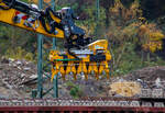 Schwellenverlegegerät Typ 159-5 (Hersteller Sonnenberg GmbH) am 08 November 2025 an einem LIEBHERR Zweiwegebagger A 922 Rail Litronic der SPITZKE SE (Großbeeren) im Rbf Betzdorf/Sieg. Hier werden zurzeit Gleise erneuert.

Der Schwellenleger ist eine innovative Neuentwicklung in Sachen Verlegetechnik. Durch das mittige Aufnehmen der Schwellen ist ein Anlegen an eine Lehrschiene möglich, wodurch kein Ausrichten der Schwellen mehr erforderlich ist.

•	Einfache Einstellung des Schwellen Typs und des Verlegeabstandes durch ein Bolzensystem.
•	Schwellentyp: Grobeinstellung der Schwellenbreite und Höhe in 10 mm Schritten. Feineinstellung der Schwellenbreite über ein Gewinde möglich.
•	Verlegeabstand: Grobeinstellung in 18 x 5 mm Schritten, Feineinstellung und größere Maß-Sprünge über ein Gewinde.
•	Die Greifer sind aus hochfestem und verschleißbeständigem Stahl (Hardox) gefertigt. Für einen besonders schonenden Umgang mit den Schwellen sind sie mit einem Hochleistungskunststoff ausgestattet.
•	Wartungsfreie und selbstschmierende Gleitkörper und Buchsen reduzieren den Wartungsaufwand auf ein Minimum.
•	Die Greiferzylinder sind mit Lasthalteventilen ausgerüstet um maximale Sicherheit zu gewährleisten.

TECHNISCHE DATEN:
Traglast: 3.300 kg
min. Schwellenbreite: 280 mm
max. Verlegeabstand: 750 mm
Gewicht Variante 159–5 für 5 Schwellen:  ca. 700 kg
Kleinste Transportabmessung (Variante 159–5): 1550 x 1000 mm
