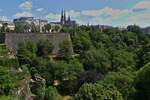 Blick über das grüne Petrustal auf die Oberstadt von Luxemburg mit der Kathedrale Notre Dame und dem Monument der „Gëlle Fra“ auf der Place de la Constitution. 23.06.2023