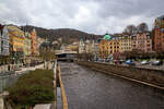 Karlsbad (Karlovy Vary) am 18.04.2023, hier in der entgegen gesetzten (nördlichen) Blickrichtung:  Rechts von dem kanalisierten Fluß Teplá (Tepl) die Marien-Magdalenenkirche und links davon die 1984